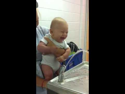Adorable laughing baby at a water fountain
