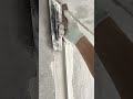 using a trowel to apply mortar along a plastic corner bead on a concrete wall to create a straight