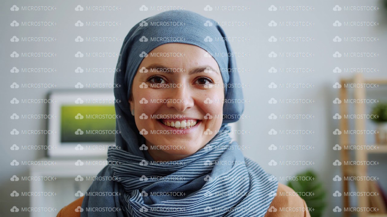 Close-up portrait of pretty Muslim woman in hijab smiling looking at camera