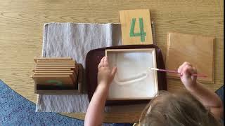 This 4 year old is writing numbers in the salt tray.