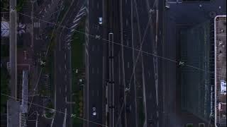 Top down shot of traffic on multilane trunk road and railway line. Vehicles passing through city at