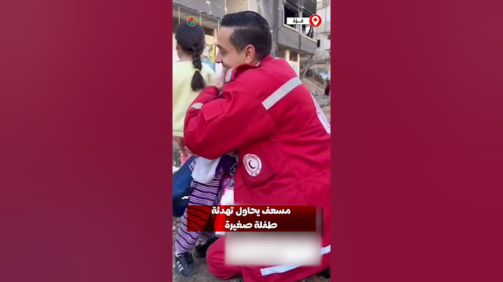 مسعف يحاول تهدئة طفلة صغيرة أثناء خروج الأهالي من مستشفى الأمل بعد حصار دام أسابيع