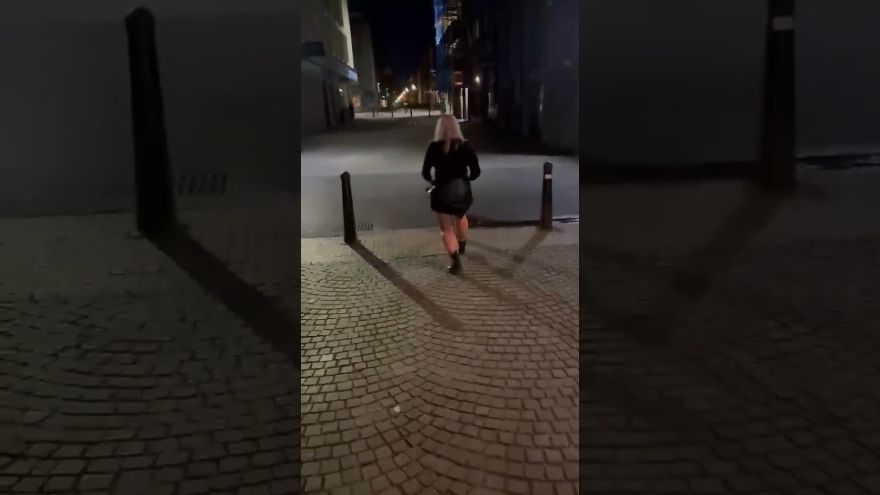 Woman jumps over street pole then falls forward and lands on stomach on pavement