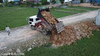 Project start first trucks dumping soil and pushing by Komatsu D20P Dozer to build foundation house