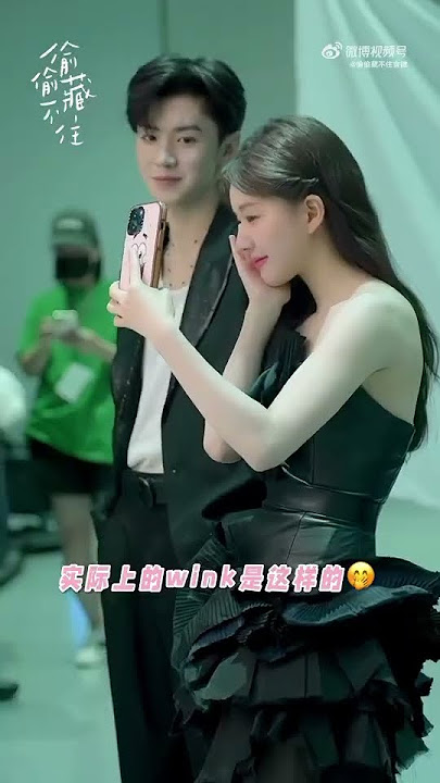 Zhao Lusi and Chen Zheyuan taking selfie behind the poster shooting
