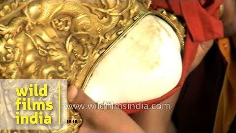 Buddhist monk blowing conch shell at Mindrolling Monastery