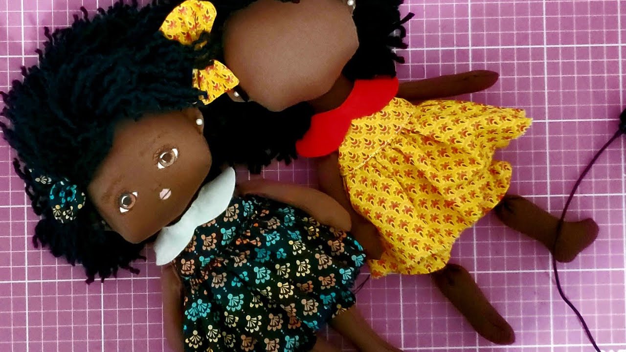 Uma boneca com um vestido preto que diz menina negra nele