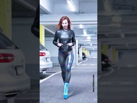 WALKING IN LEATHER HIGH HEELS BOOTS AND LEGGINGS AROUND A PARKING HALL.