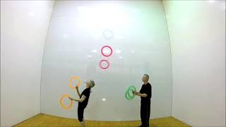 Couple Juggles And Passes Rings To Each Other As Woman Stands Facing Backward Toward Man - 1213701-6