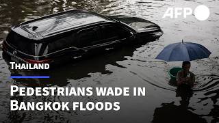 Pedestrians wade through flooded Bangkok roads after days of rain | AFP