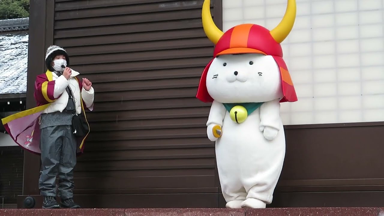 合羽を脱いで招き猫伝説を演じます