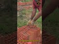 a construction worker uses a homemade brick lifter or special tool to move large perforated bricks