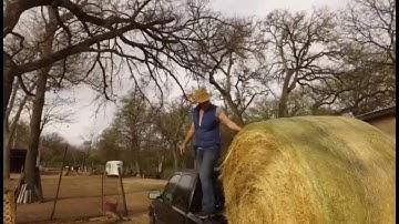 How to unload a round bale of hay out of the back of a truck into a barn