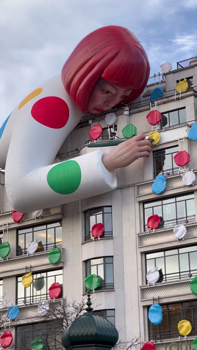 People use their smartphones to take pictures of the Yayoi Kusama robot  painting spots on the window of the luxury retailer Louis Vuitton's Fifth  Avenue store, New York, NY, January 9, 2023.