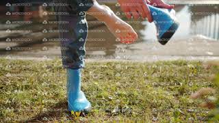 Close-Up Of Hand Taking Off Rubber Boot From Bare Foot And Pouring Out Water