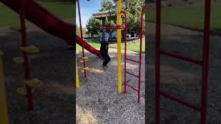 Boy hangs from pole at playground then swings himself and bumps a sensitive area