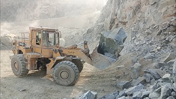 Heavy machine rocks loading in action: caterpillar loader 966E big rocks loading damper and trolleys