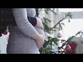 Happy young family. Husband hugs him pregnant wife near beautiful decorated Christmas tree by the