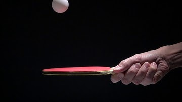 hand holding table tennis racket and bouncing ping pong ball