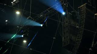 Professional audio speakers and stage lighting gear hanging at a music event