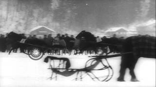 Spectators cheer the riders as they ride farm horse sledges on a frozen lake in A...HD Stock Footage