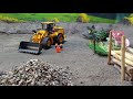 Rc loader loading gravel into rc dump truck at quarry site.
