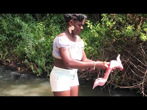 African village  girl slaughtering rabbit barefoot near the river