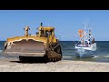 Cat d10n dozer pulling up fishing boats to the beach at thorup strand