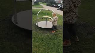 Little girl pushes merry go round that spins and metal bar hits her on head after twin sister enters