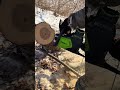 cutting wood log using a cordless electric chainsaw in a snowy outdoor area with sawdust flying