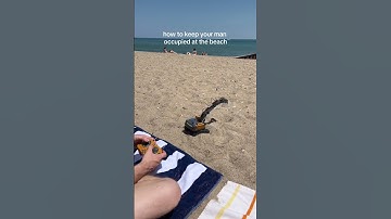 Guy is playing with a remote-controlled excavator at the beach!