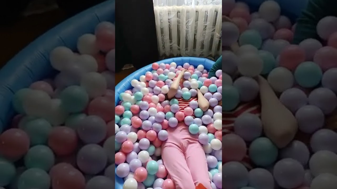 девочка играет в бассейне из шариков