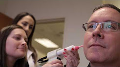 photo of two female workers inserting an instrument into the ear of a man