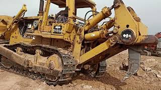 Komatsu D155A bulldozer ripper to penetrate stone and loosen it up and front blade pushes stone.