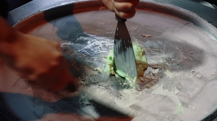 a person making ice cream on the metal surface alo...