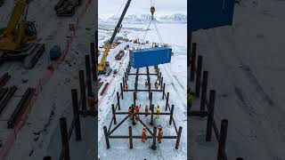 A modular shipping container research station on a flat, icy Antarctic ice shelf.