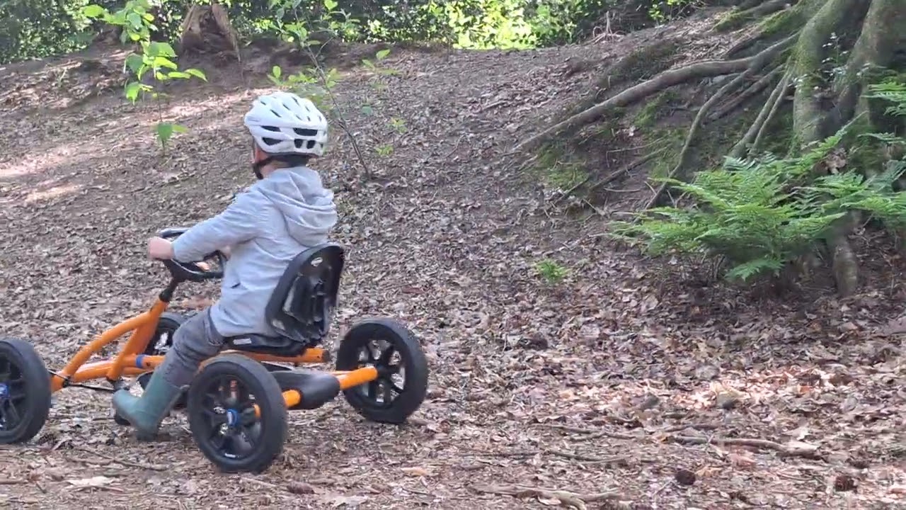 Girl on green bike rides down dirt hill and faceplants after brother rides go kart