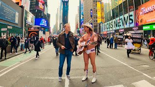 The Naked Cowboy singing “Take me home. Country roads” in Times Square.