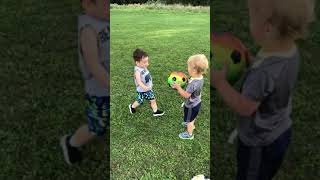 Boy attempts to kick soccer ball from friends hand but accidently hits him on a a sensitive area