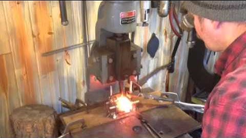 Punching an axe eye under the fly press, blacksmith forging