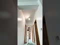 using a paint roller to apply a fresh layer of white paint on the ceiling of a hallway for a clean
