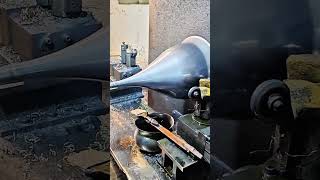 Lathe carves conical metal, shavings scatter under steady tool