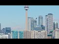 Small turboprop airplane flying over Toronto skyline with CN Tower in background on a clear sunny