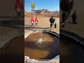 The man uses a long torch to ignite the natural gas bubbling up from the water