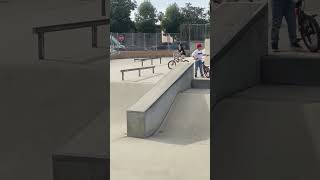 Girl rides bike down ramp at skatepark then falls forward and faceplants