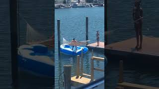 Guy attempts to jump onto hammock but falls into the water
