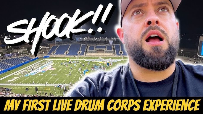 A surprised person with a beard is shown in the foreground, looking out at a stadium where a drum corps performance is taking place. The text overlay expresses excitement about their first live drum corps experience.