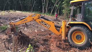 jcb 3dx cleaning land by removing grass and taking out huge roots of fellen trees