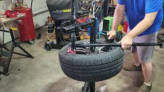 Harbor Freight Pittsburgh black manual tire changer mounting low profile tire using duck head.
