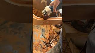 smoothing the curved surface of a long wooden frame precisely using an electric angle grinder